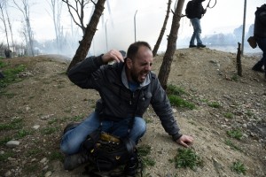 A man on the Greek side of the border runs away after Macedonian police fired tear gas at a group of the refugees and migrants who tried to push their way into Macedonia, breaking down a border gate near the northern Greek village of Idomeni on Monday, Feb. 29, 2016. No arrests or injuries were reported. About 6,500 migrants are stuck on the Greek-Macedonian border at Idomeni, waiting to travel north, but Macedonia is only admitting a trickle. (AP Photo/Giannis Papanikos)