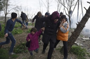 A woman holds her children on the Greek side of the border as they run away after Macedonian police fired tear gas at a group of the refugees and migrants who tried to push their way into Macedonia, breaking down a border gate near the northern Greek village of Idomeni on Monday, Feb. 29, 2016. No arrests or injuries were reported. About 6,500 migrants are stuck on the Greek-Macedonian border at Idomeni, waiting to travel north, but Macedonia is only admitting a trickle. (AP Photo/Giannis Papanikos)