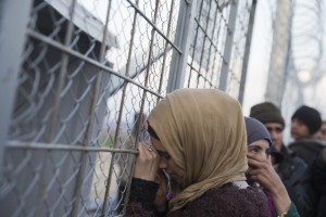 A Syrian young woman leans on the door through which refugees cross for Macedonia in the Greek border station of Idomeni, Sunday Feb. 28, 2016. More than 5500 refugees and migrants are stuck at the Greek-Macedonian border. (AP Photo/Petros Giannakouris)
